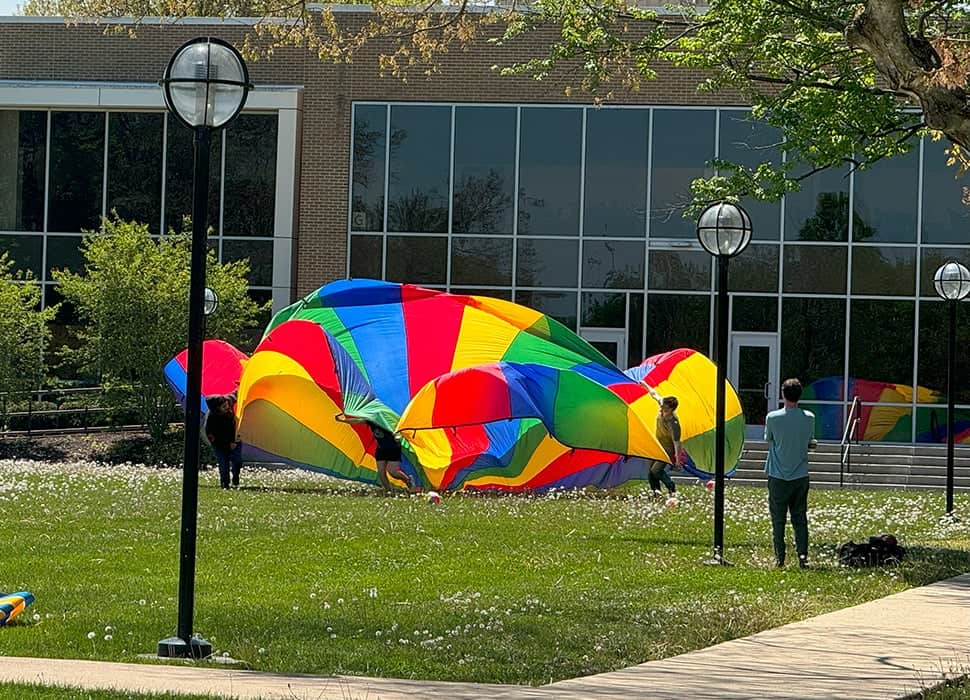 Student games on the lawn with a colorful parachute